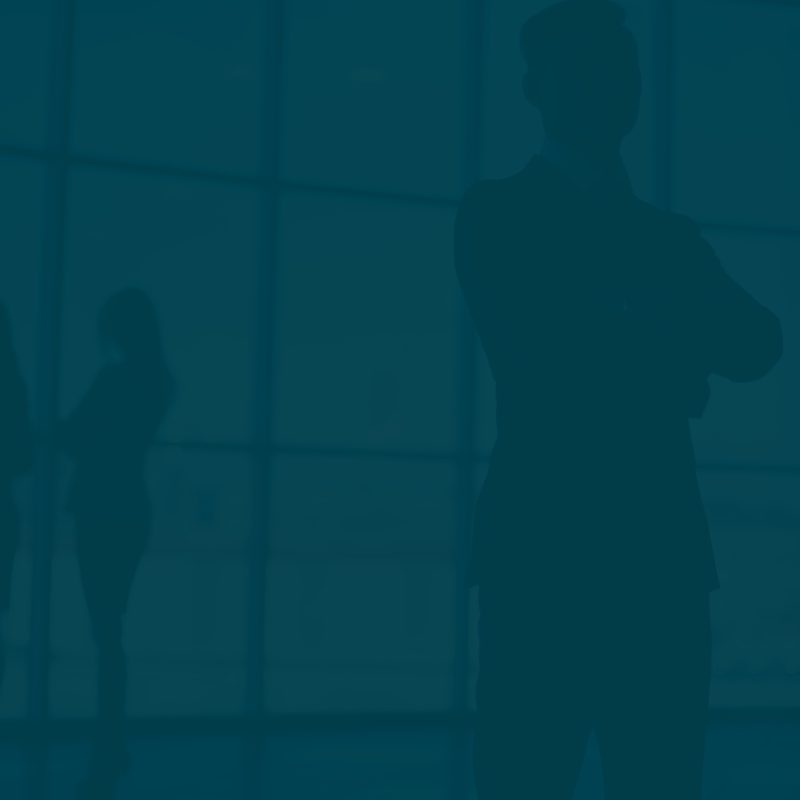 Group of silhouetted professionals engaged in conversation near large office windows during daylight